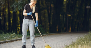 Woman collects leaves and cleans the park Volunteer collects leaves. Woman in a park. People cleans the park